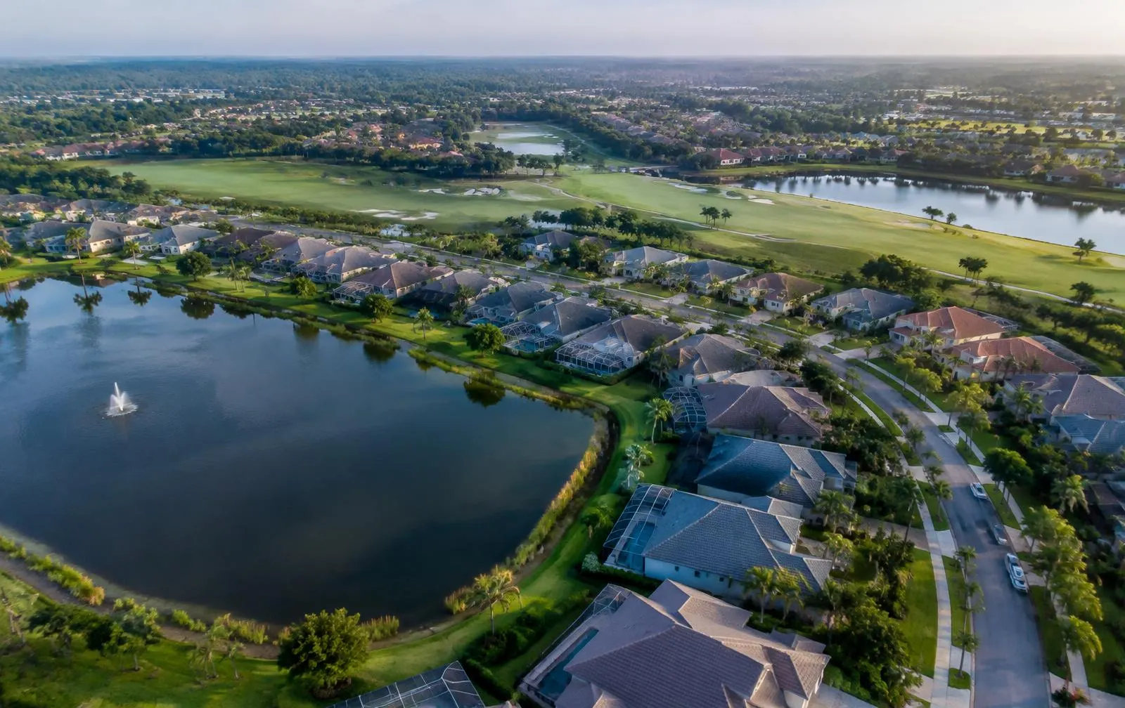 Aerial view of a lakefront Florida neighborhood with screened pools