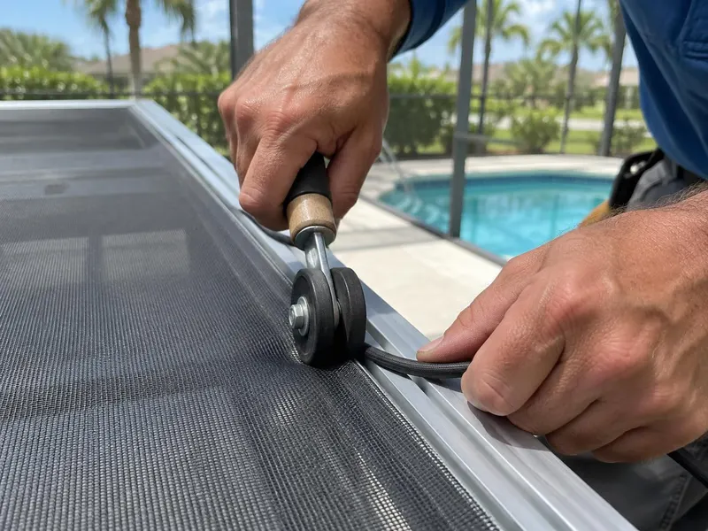 Technician repairing screen on a pool enclosure frame